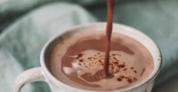 Gorąca czekolada jest wlewana z dzbanuszka do filiżanki